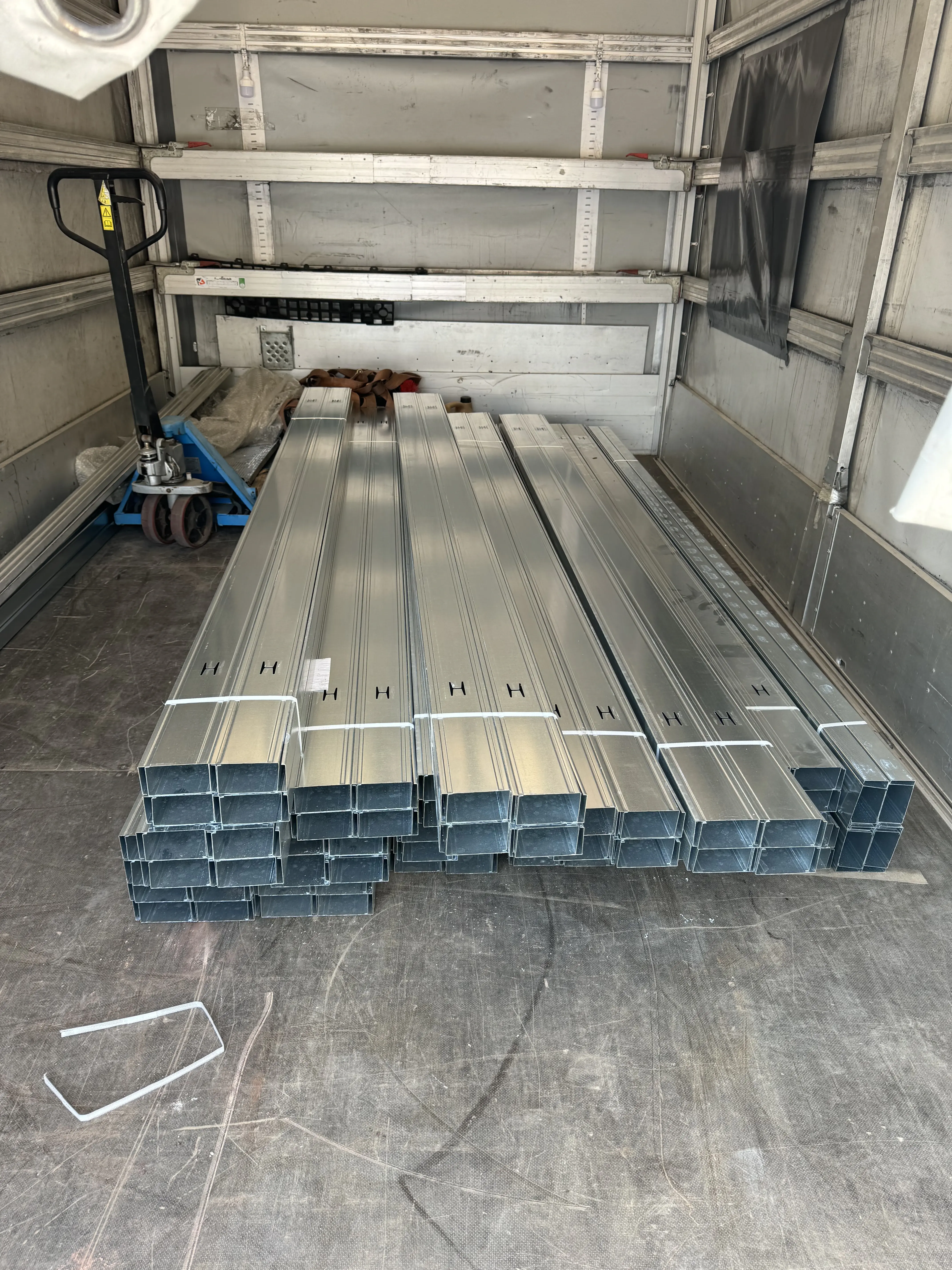 Związane paczki metalowych profili do płyt gipsowo-kartonowych na pace ciężarówki