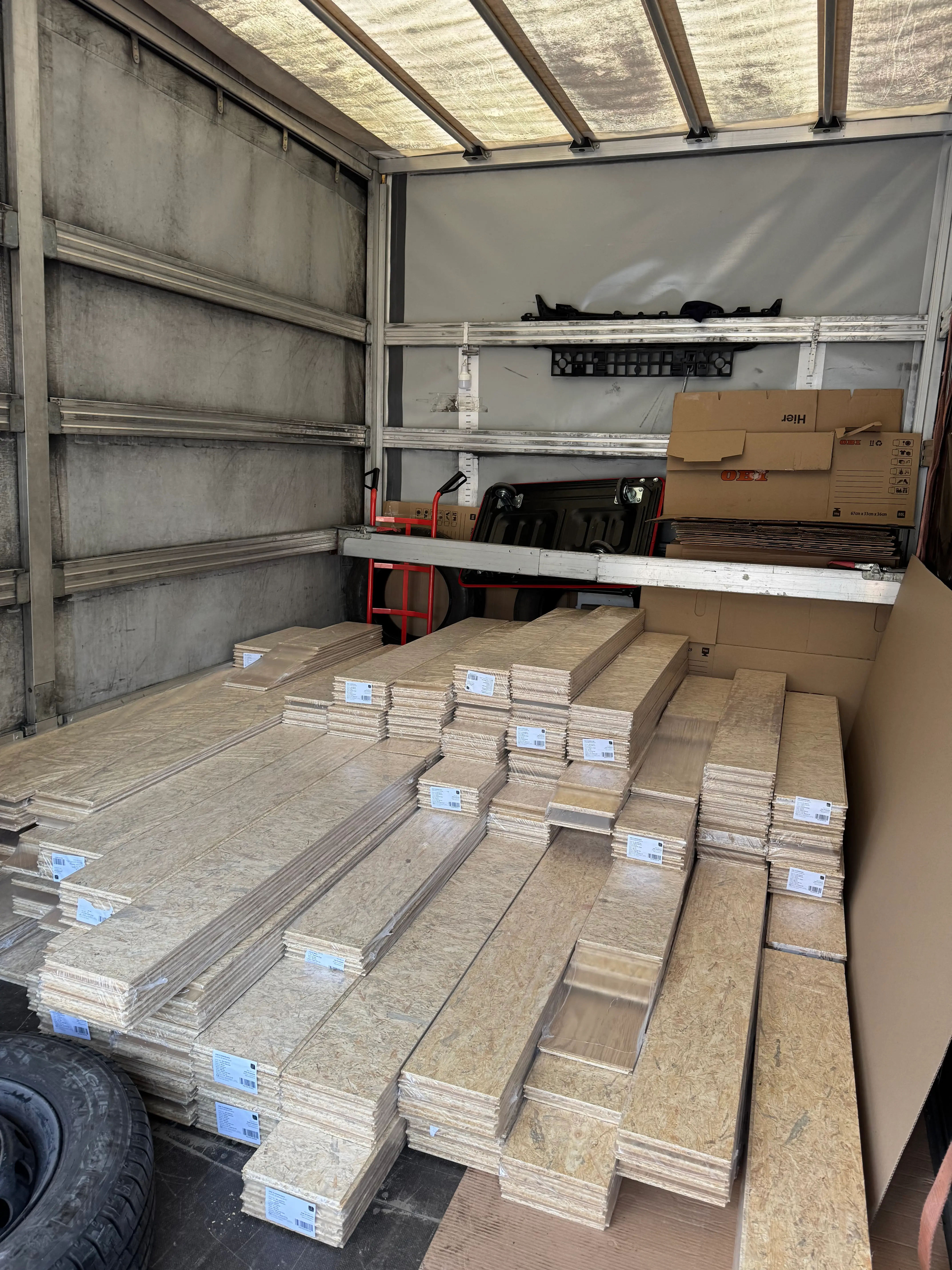 Wnętrze samochodu dostawczego z ułożonymi stosami drewnianych paneli lub płyt